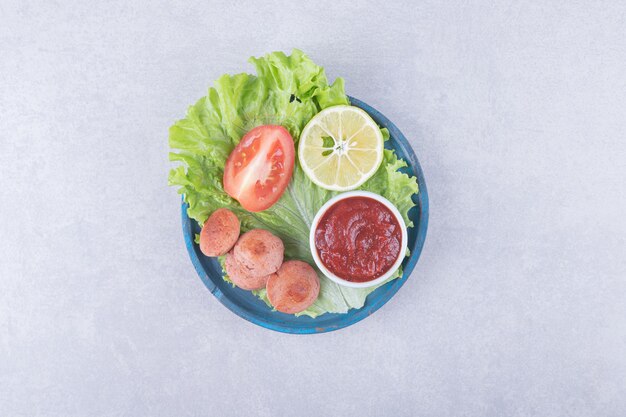 Tasty grilled sausages and ketchup on blue plate.