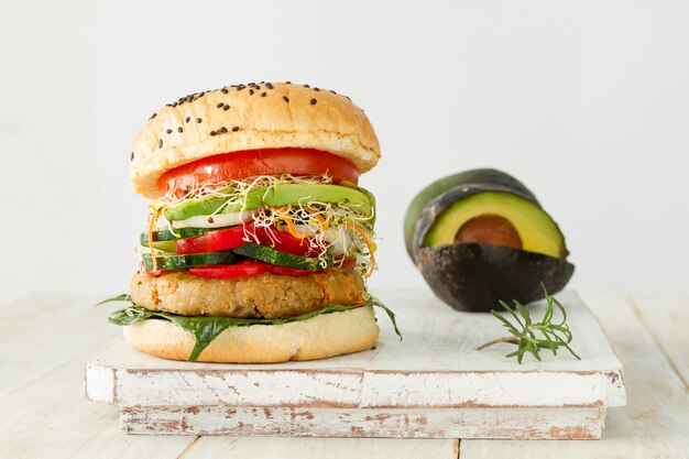 Tasty hamburger and avocado on wooden board