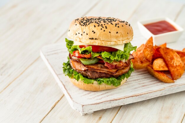 Tasty hamburger with fries on wooden board