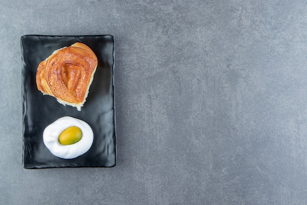 Tasty homemade fresh bun on black plate.