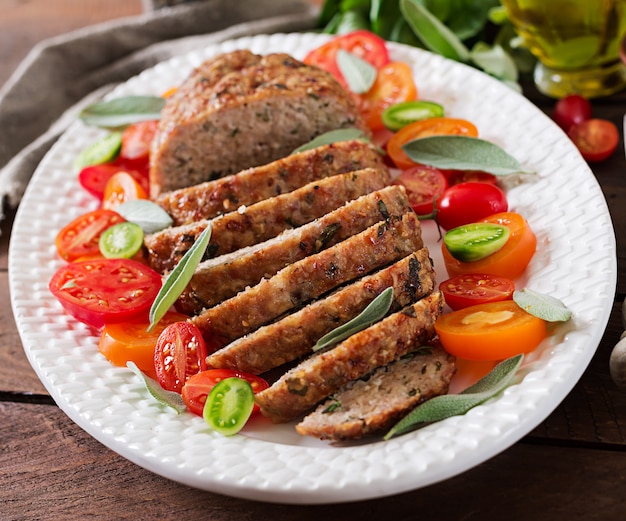 Tasty homemade ground  baked turkey meatloaf in white plate on wooden table. Food american meat loaf.