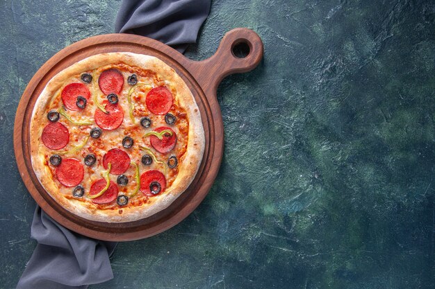 Tasty homemade pizza on wooden board on dark color towel on isolated dark surface