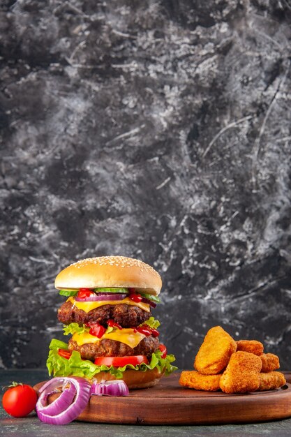 Tasty homemade sandwich tomatoes pepper on wooden cutting board onions tomato with stem chicken nuggets on dark color surface