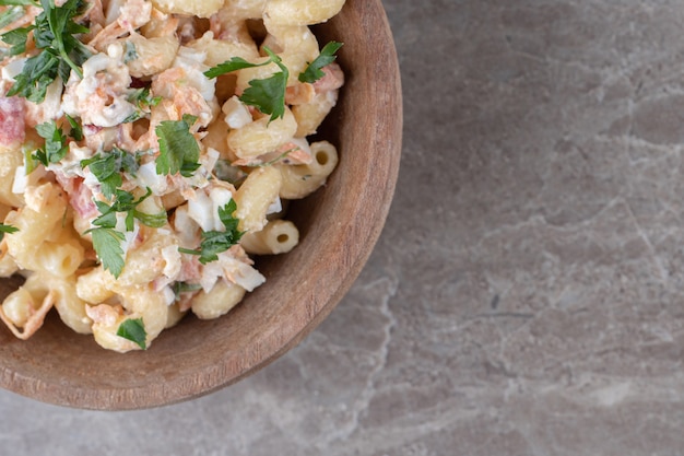 Tasty macaroni with mixed salad in wooden bowl.