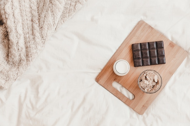 Tasty meal on cutting board standing on bedsheet