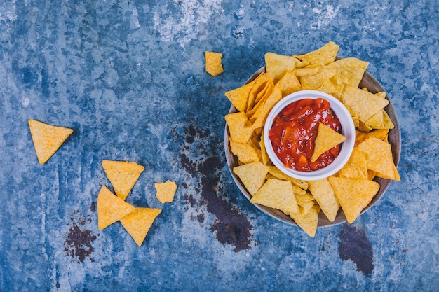 Tasty mexican nachos with salsa sauce on weathered background