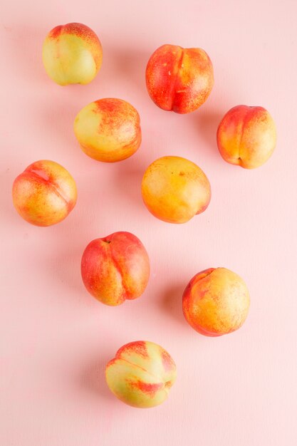 Tasty nectarines on a pink surface. flat lay.