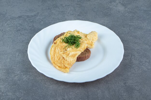 Tasty omelette with bread on white plate.