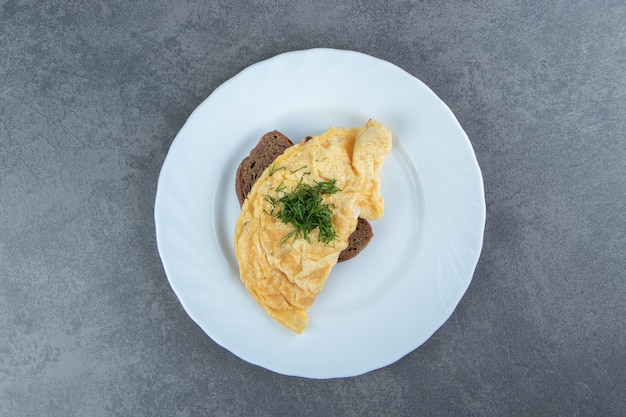 Tasty omelette with bread on white plate