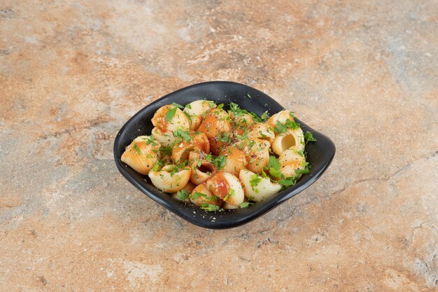 Tasty pasta in bowl with tomato sauce and parsley