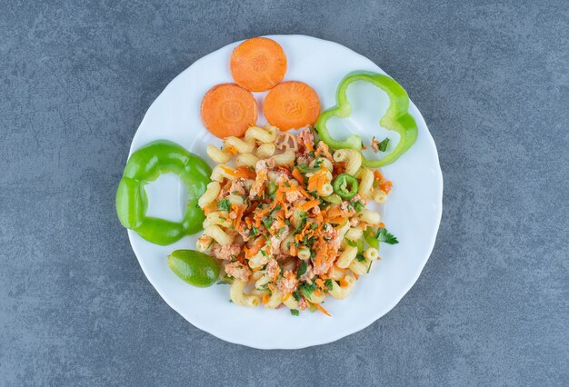 Tasty pasta with chopped vegetables on white plate. 