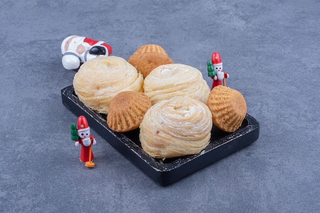 Foto gratuita gustosi pasticcini con giocattoli di natale su una superficie grigia