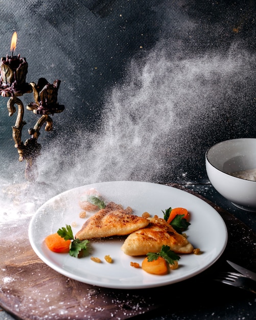 Foto gratuita gustosa pasticceria affettata insieme a pezzi di carote arancioni e foglie verdi all'interno del piatto bianco sulla superficie della luce