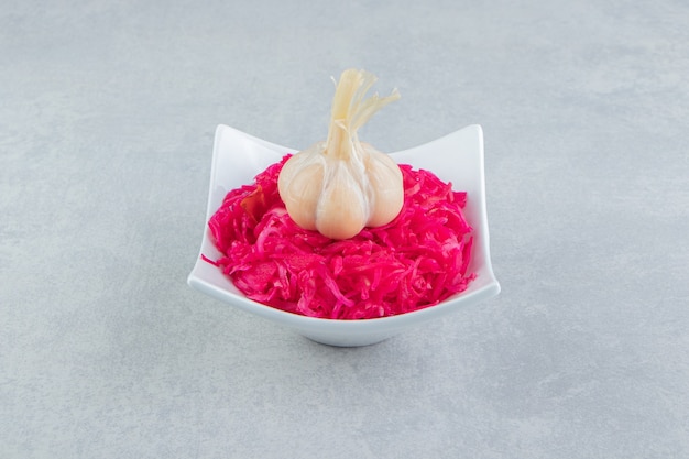 Tasty pickled cabbage with garlic in white bowl.  