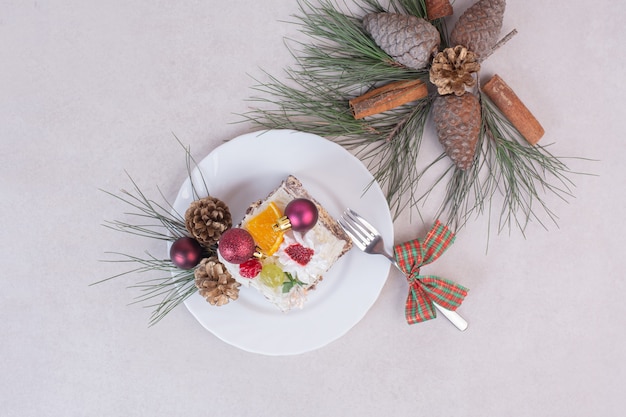 Tasty piece of cake with pinecones and branch of tree 