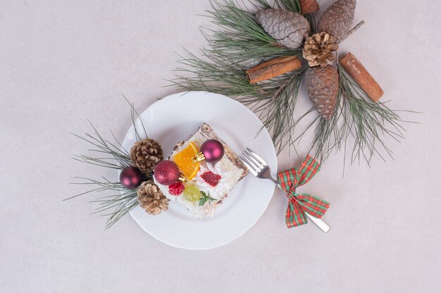 Tasty piece of cake with pinecones and branch of tree 