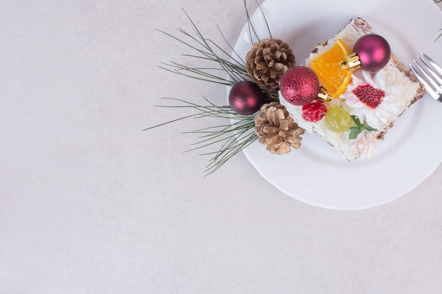 Tasty piece of cake with pinecones and branch of tree 