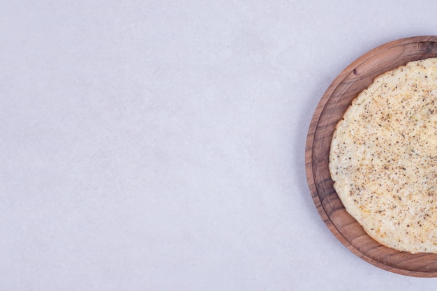 Tasty pizza on wooden plate on white surface