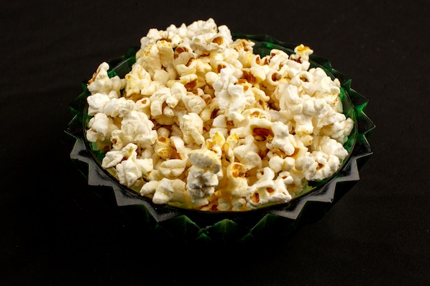 Tasty popcorn bright yummy salted inside round plate on a dark