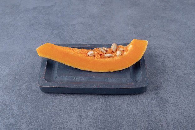 Tasty pumpkin pieces on the board, on the marble surface.