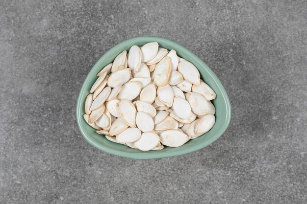 Tasty pumpkin seeds in blue bowl.