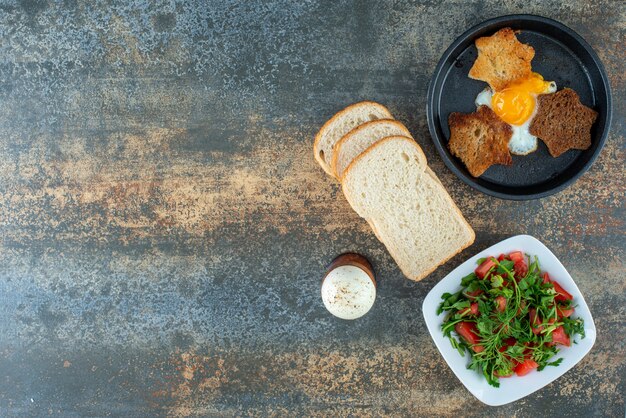Вкусный салат с нарезанным хлебом и вареными яйцами на мраморном фоне