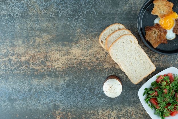 Tasty salad with sliced breads and boiled eggs on marble background