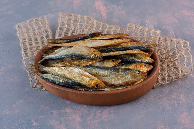 Вкусная соленая рыба на деревянной тарелке, на мраморном фоне.