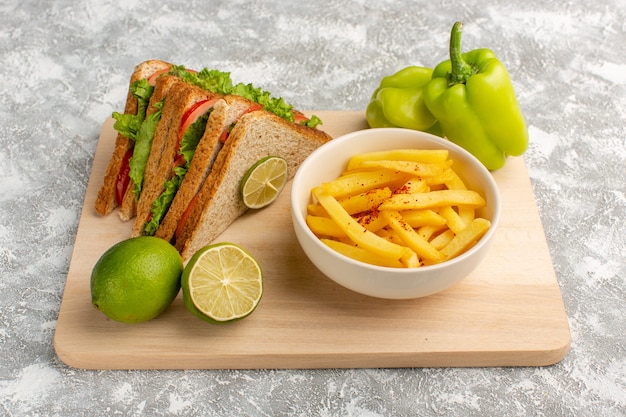 tasty sandwich along with french fries lemon and green bell-pepper