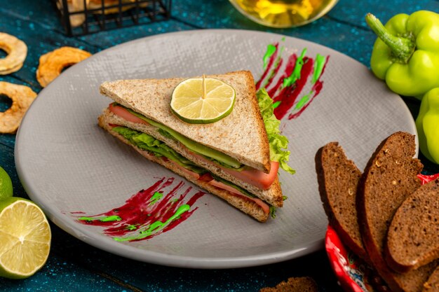 вкусный бутерброд с зеленым салатом, ветчиной и помидорами в качестве начинки на синем