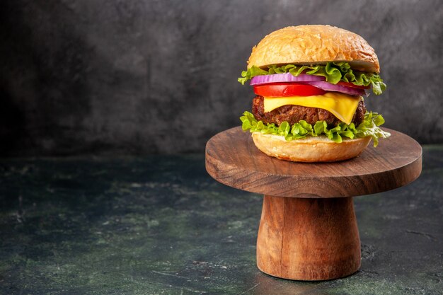 Вкусный бутерброд на деревянной разделочной доске слева на поверхности темного цвета со свободным пространством