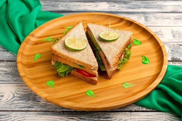 tasty sandwiches with green salad ham and tomatoes on grey