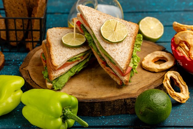 tasty sandwiches with green salad tomatoes along with green bell-pepper bread and lemon on blue