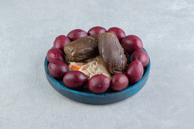 Tasty sauerkraut, eggplant and plums on blue plate.  