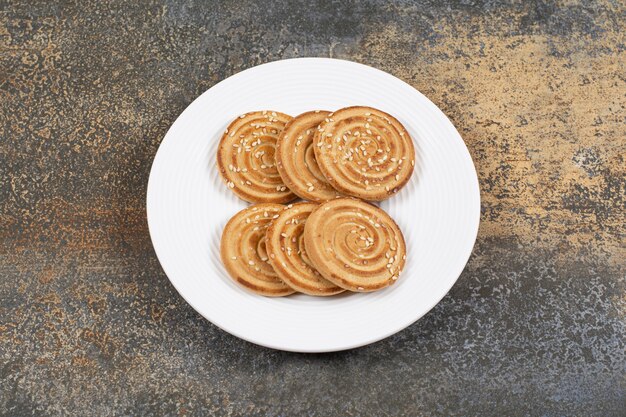 Tasty sesame seeds biscuits on white plate.