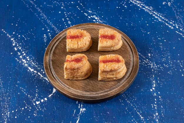 Tasty sliced cakes with jam placed on wooden board