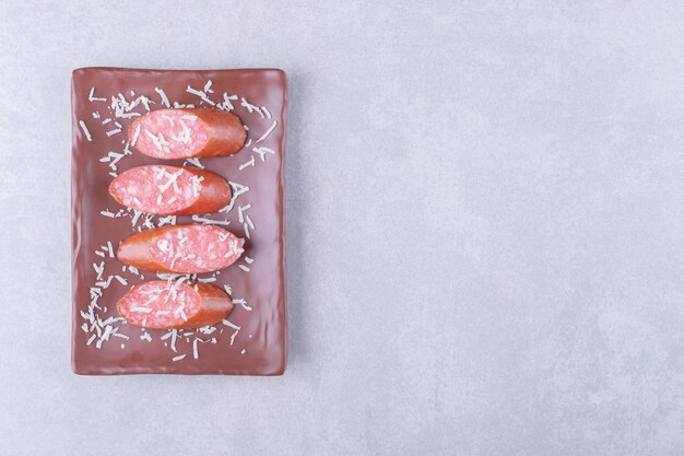 Tasty smoked sausages on brown plate.