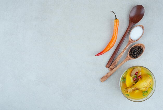 Tasty soup with spices and chili pepper on white table.