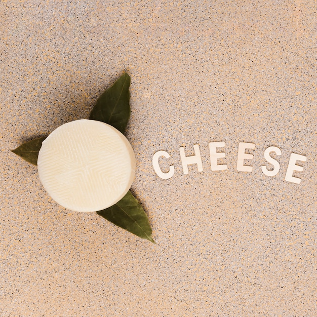 大理石の背景にチーズのテキストと月桂樹の葉の上のおいしいスペイン語マンチェゴチーズ