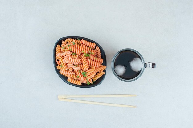 Tasty spiral macaroni with iced tea and chopsticks.