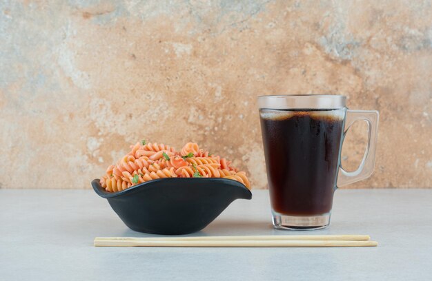 Tasty spiral macaroni with iced tea and chopsticks.