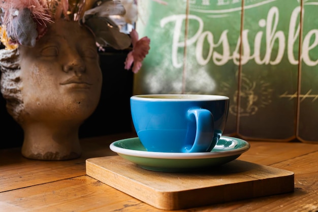 Tasty steamy cup of coffee with on a wooden table in a coffee shop wooden card and sculpture