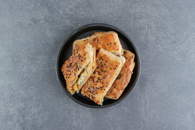 Tasty stuffed pastries on black plate.