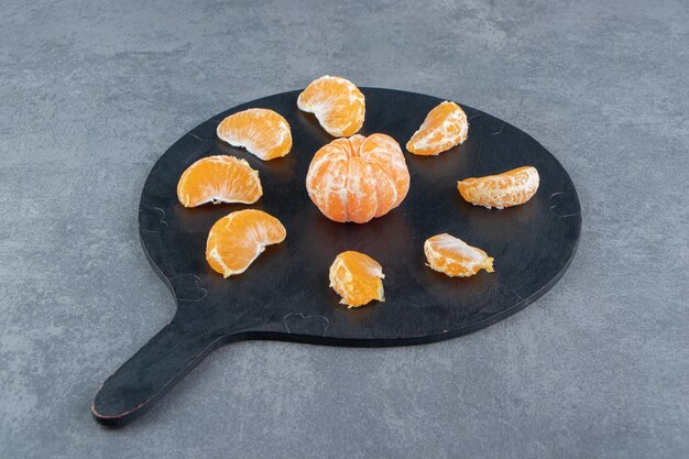 Free photo tasty tangerine slices on cutting board.