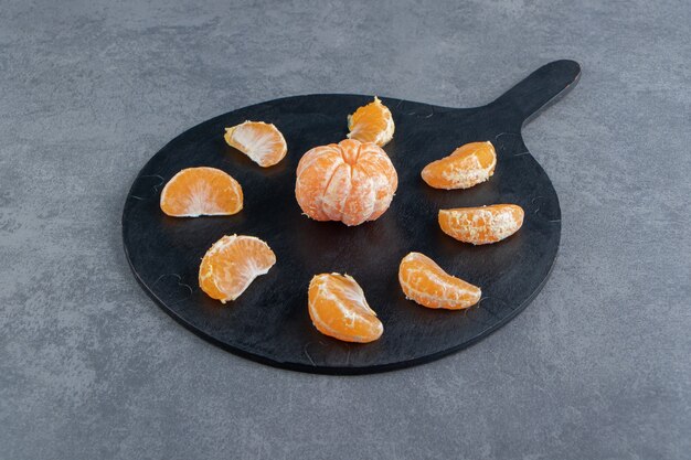 Tasty tangerine slices on cutting board.