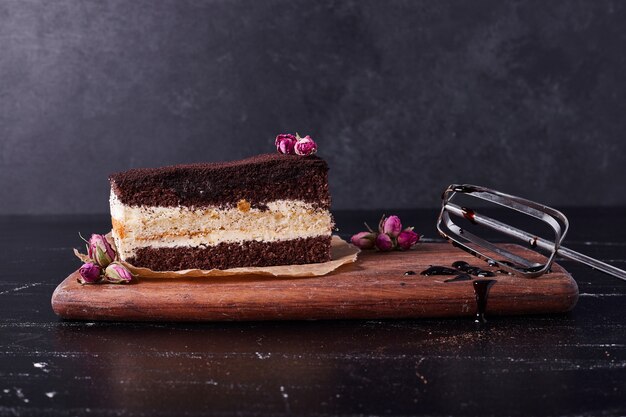 Tasty tiramisu cake with flower seed on dark background. 