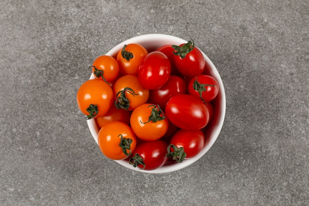 Tasty unripe tomatoes in the bowl , on the marble.