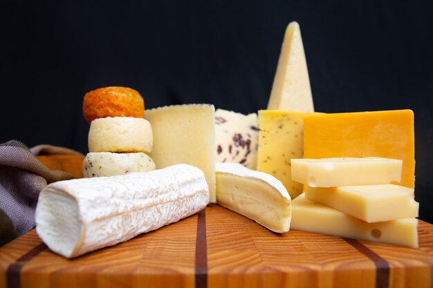 Tasty various cheeses laying on wooden board