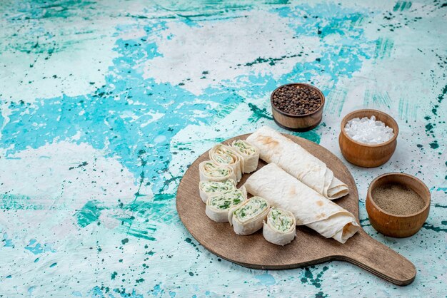 tasty vegetable rolls whole and sliced with greens and seasonings on bright-blue floor food meal roll vegetable