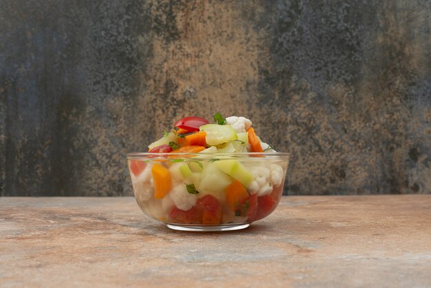 Tasty vegetables on glass plate on marble.